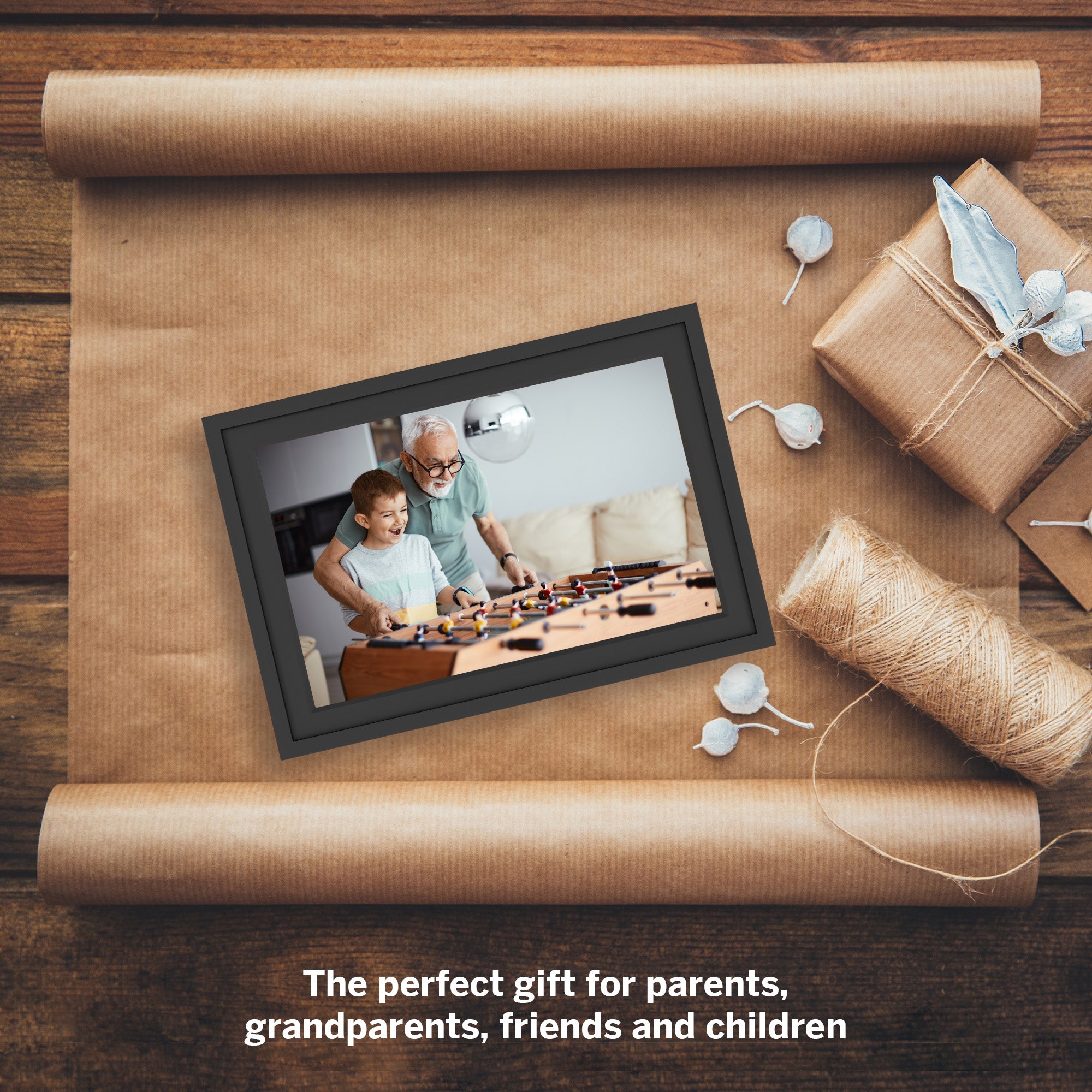 Digital photo frame on brown paper with wrapped gift and decorative elements