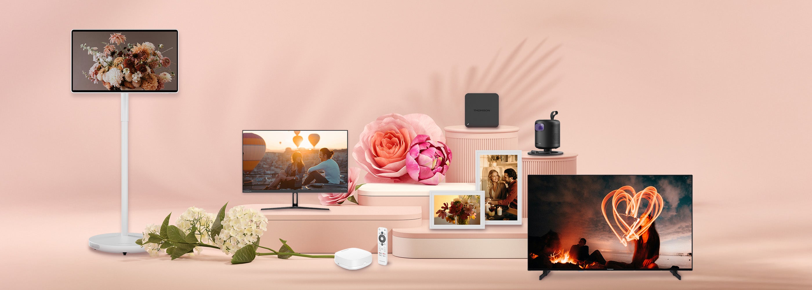 Smart home devices including a TV, projectors, and streaming devices, smart photo frames on a pink background with decorative elements.