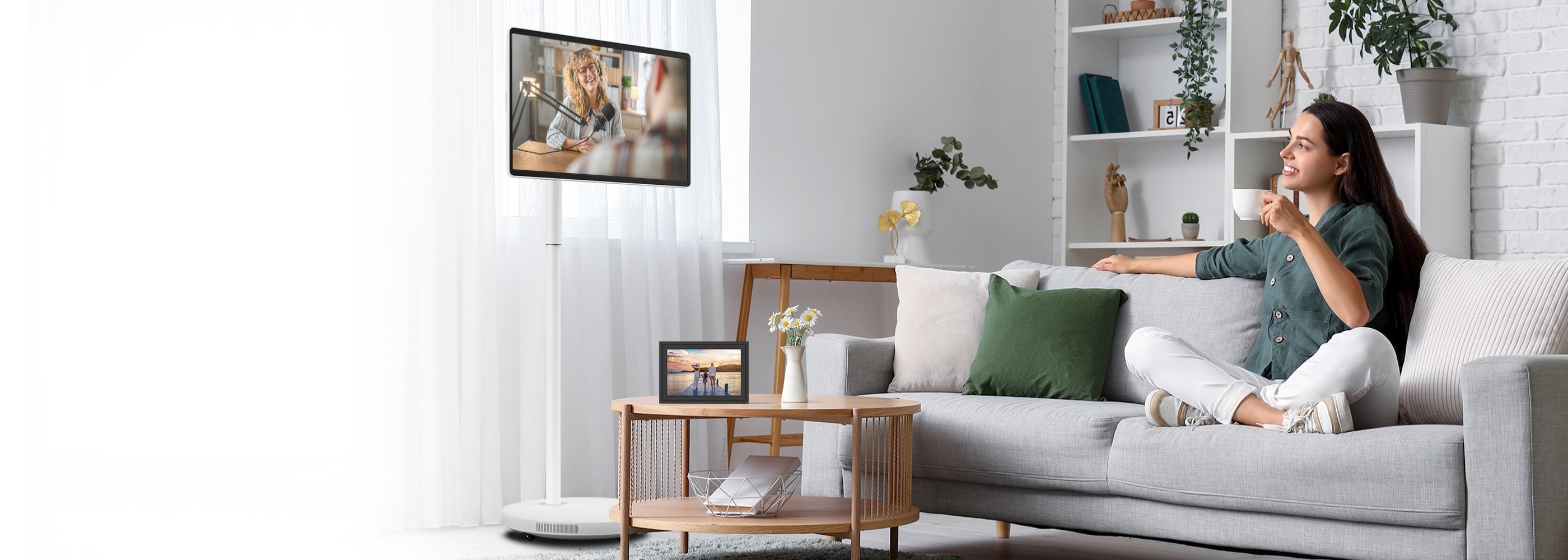 Woman sitting on a couch in a modern living room watching portable TV.