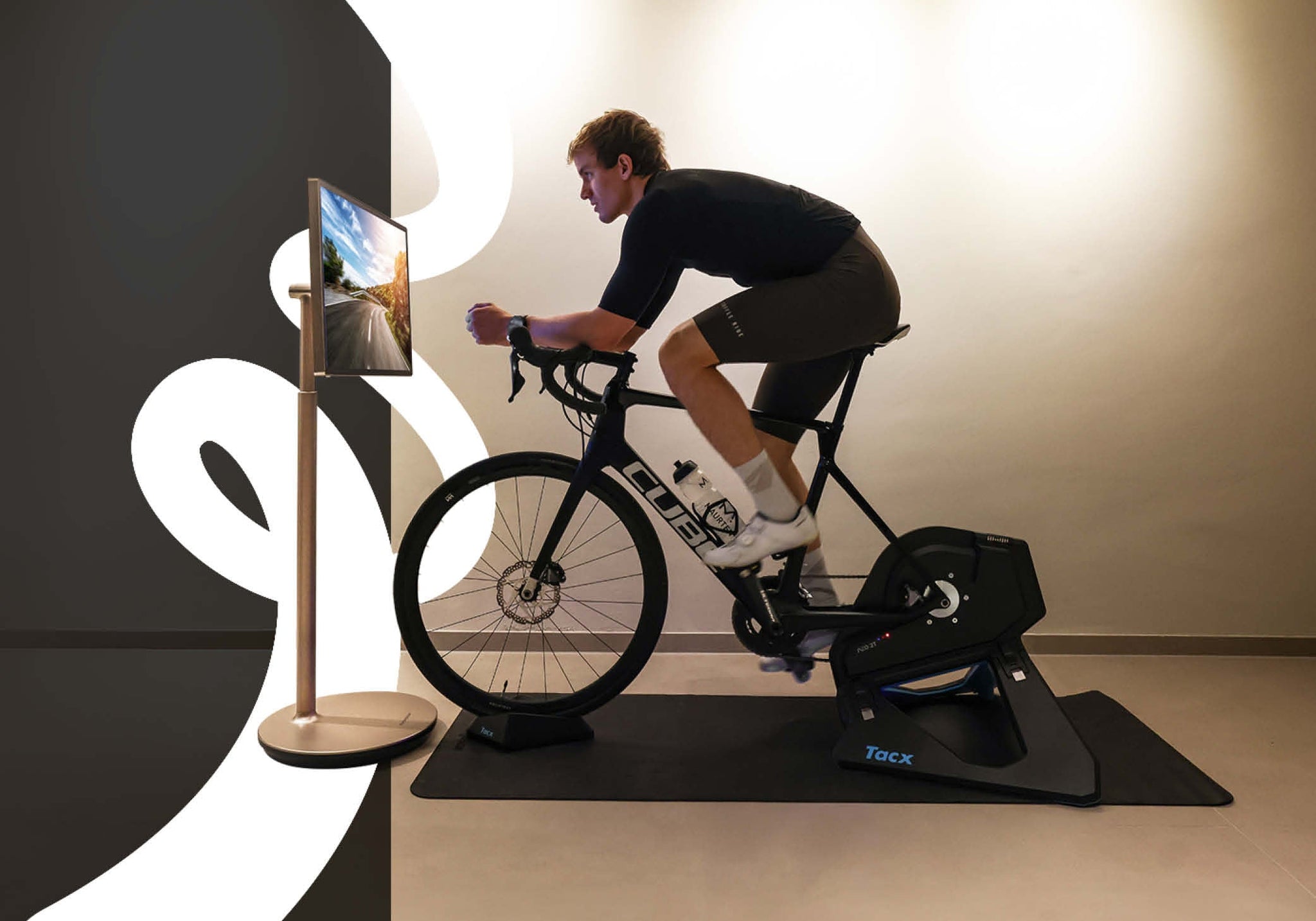 Indoor training session: Nico Rauchenwald pedals on a stationary bike, engaged with the Thomson Go Plus mobile TV in front of him.