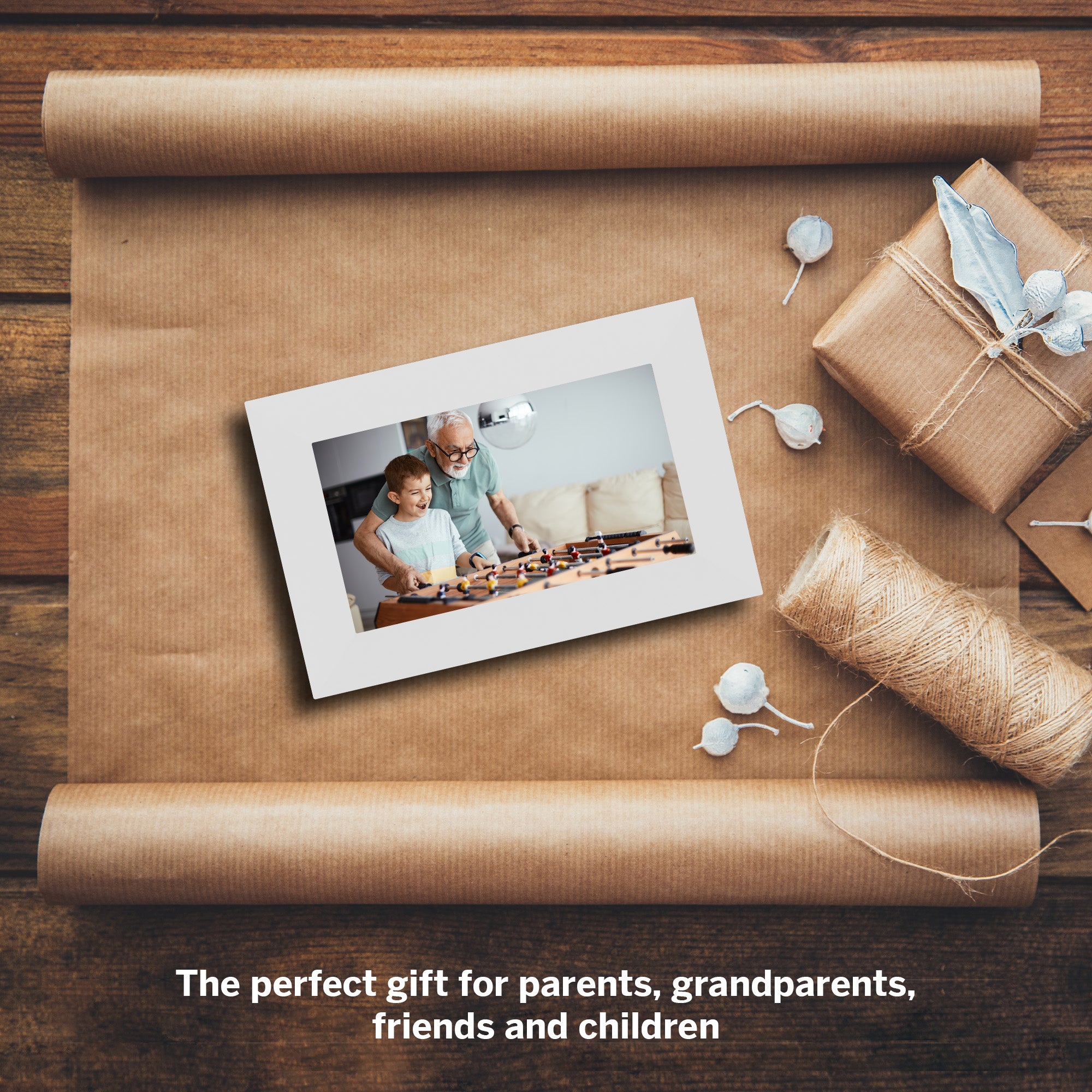 Gift with photo frame and wrapped present on brown paper, wooden background