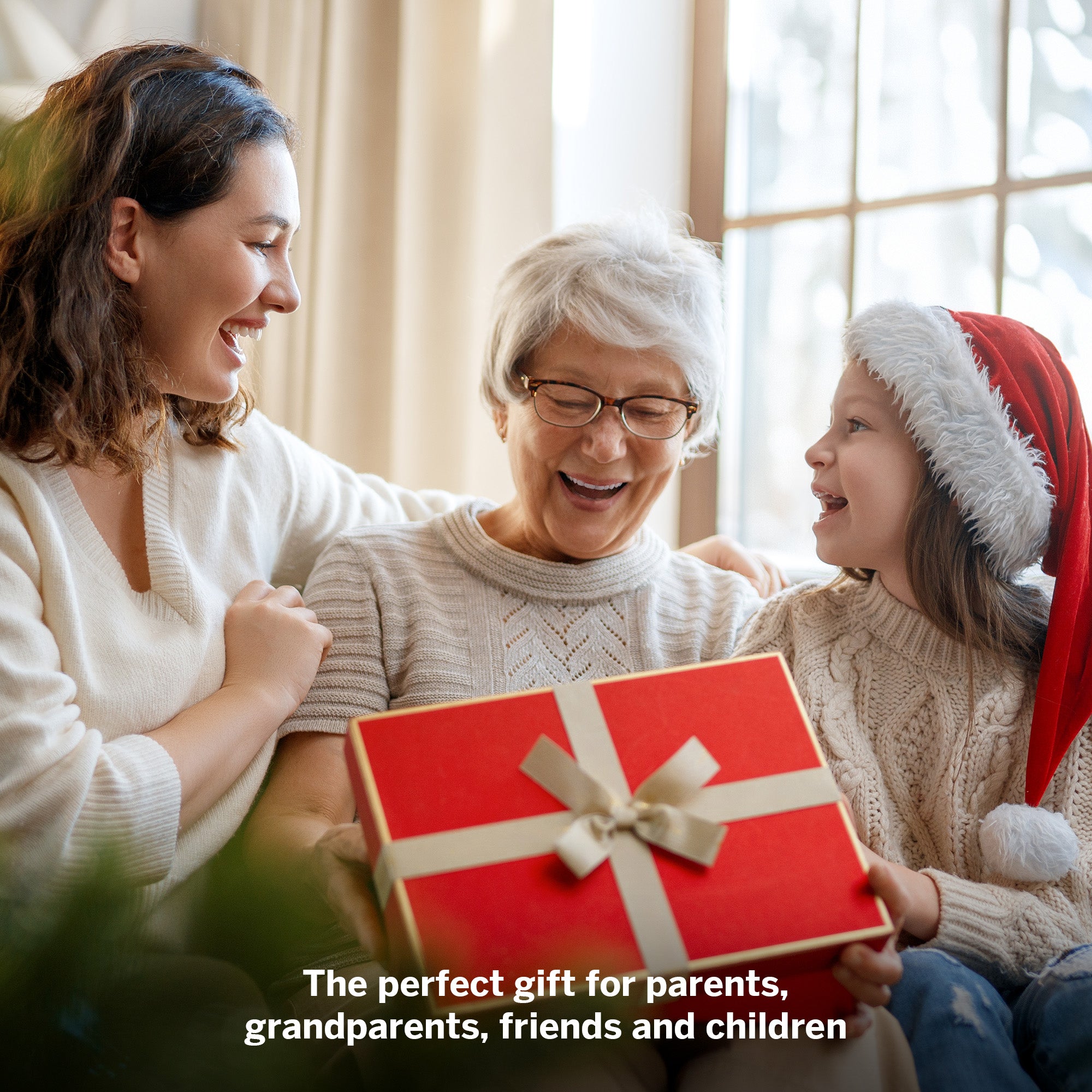 Woman, older woman, and child with a red gift box indoors.
