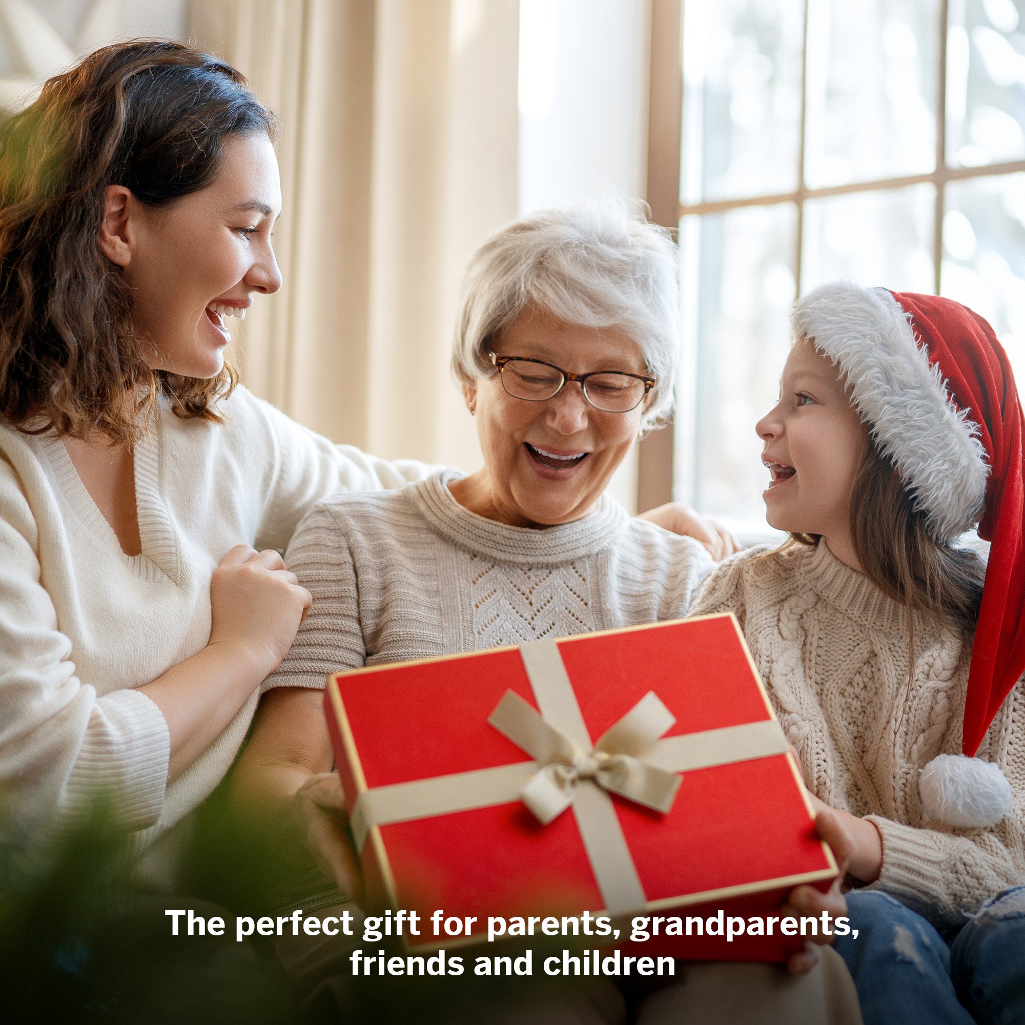 Woman, older woman, and child with a red gift box indoors.