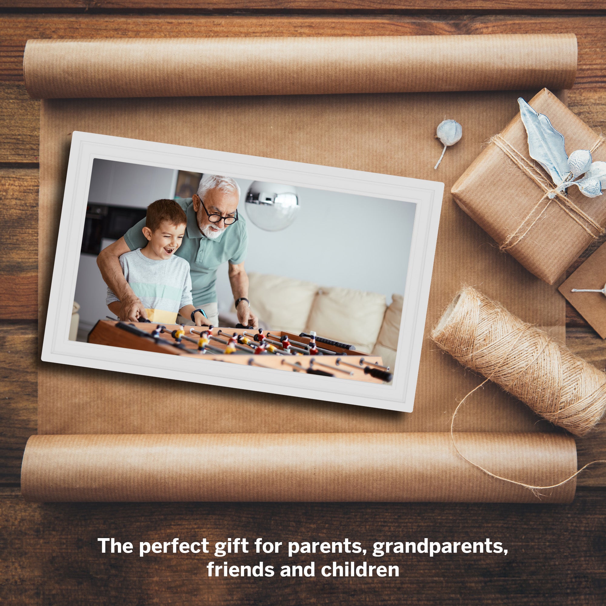 Framed photo of a man and child playing foosball with gift wrapping and ribbons on a wooden surface.