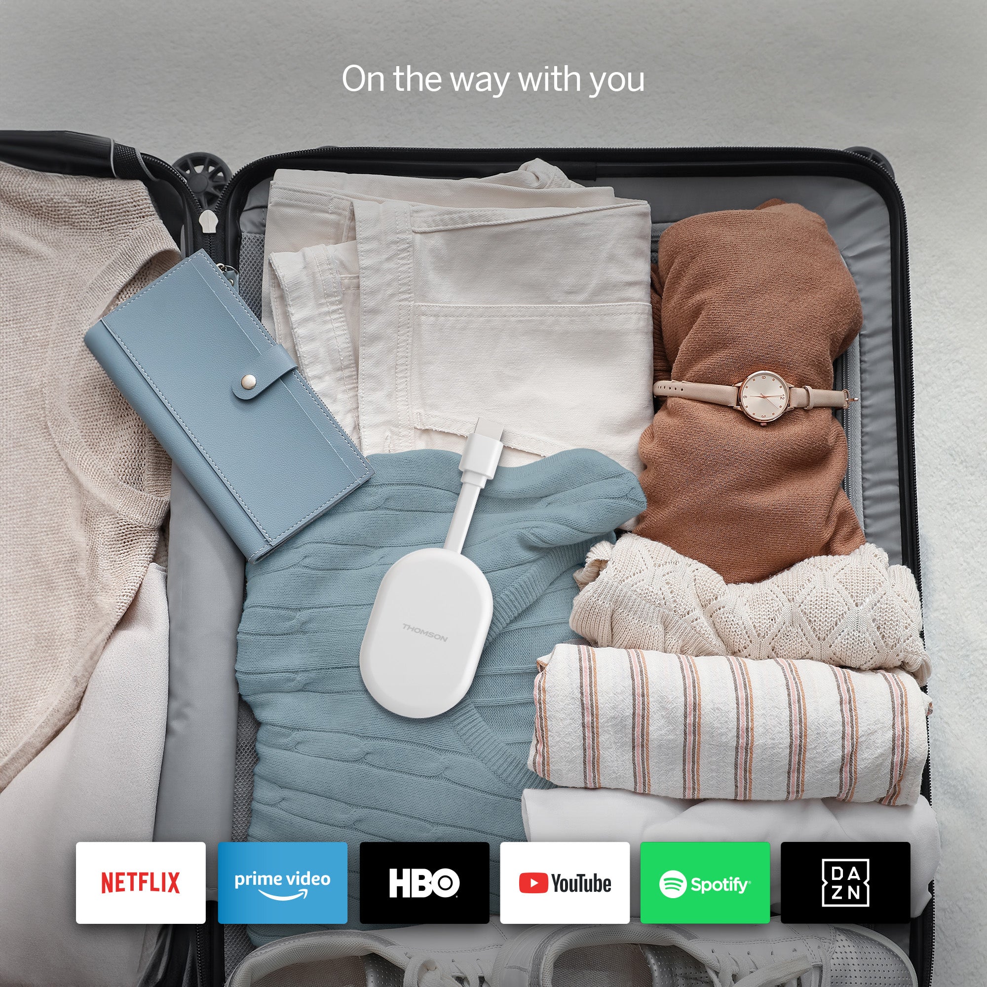 Open suitcase with folded clothes and electronic devices, featuring streaming service logos at the bottom.