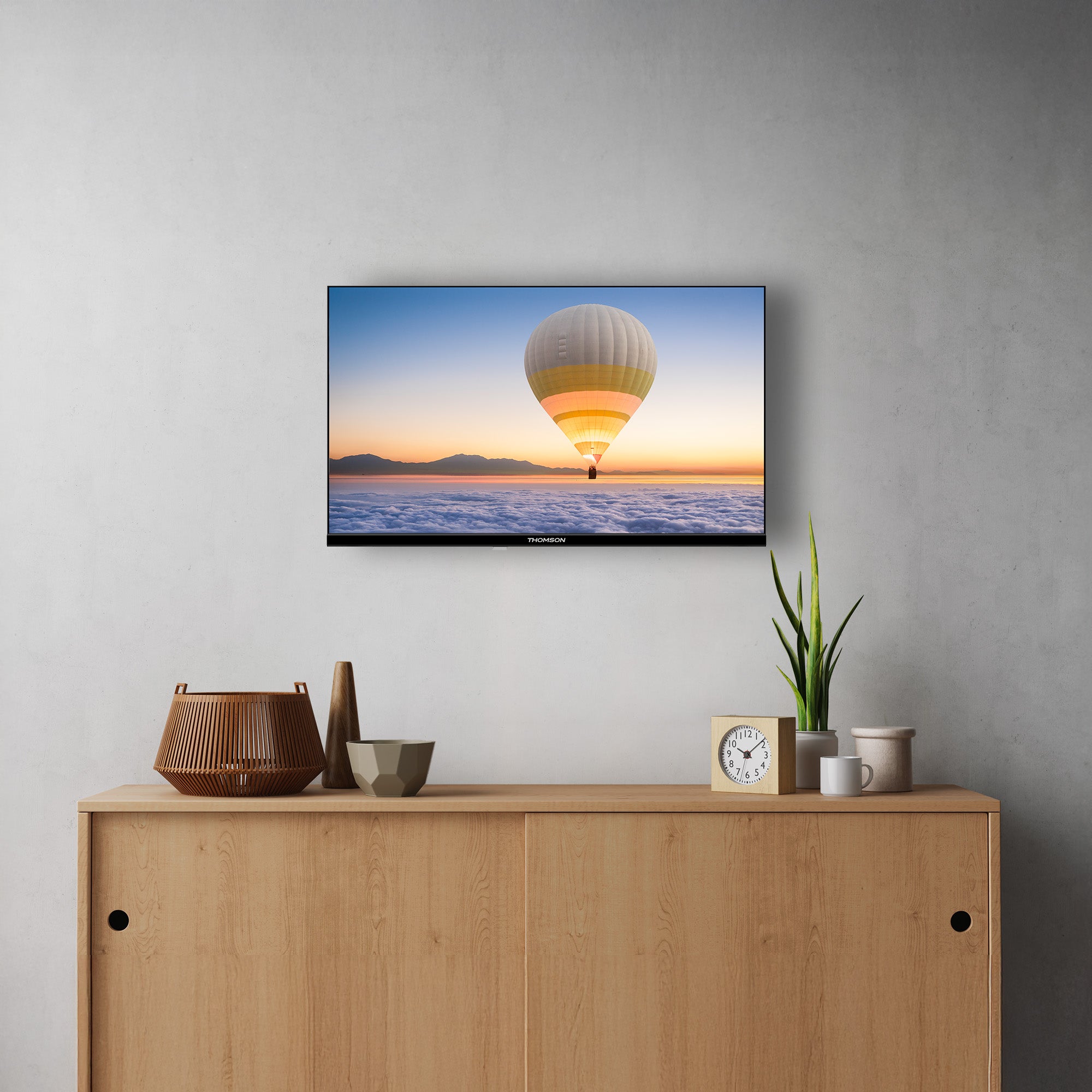 Smart TV displaying a hot air balloon over water with a wooden cabinet and decorative items below.