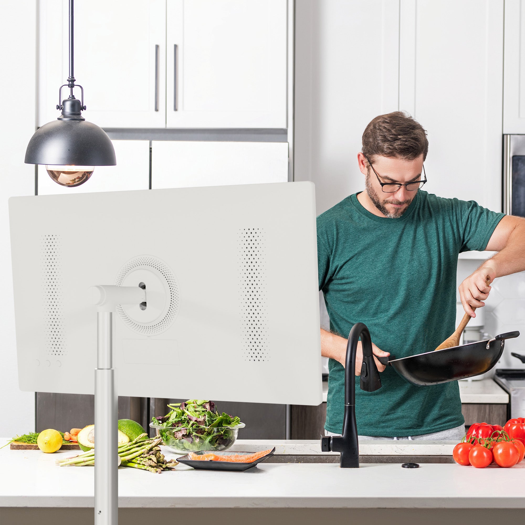 Man cooking in a kitchen with a white portable TV in front of him