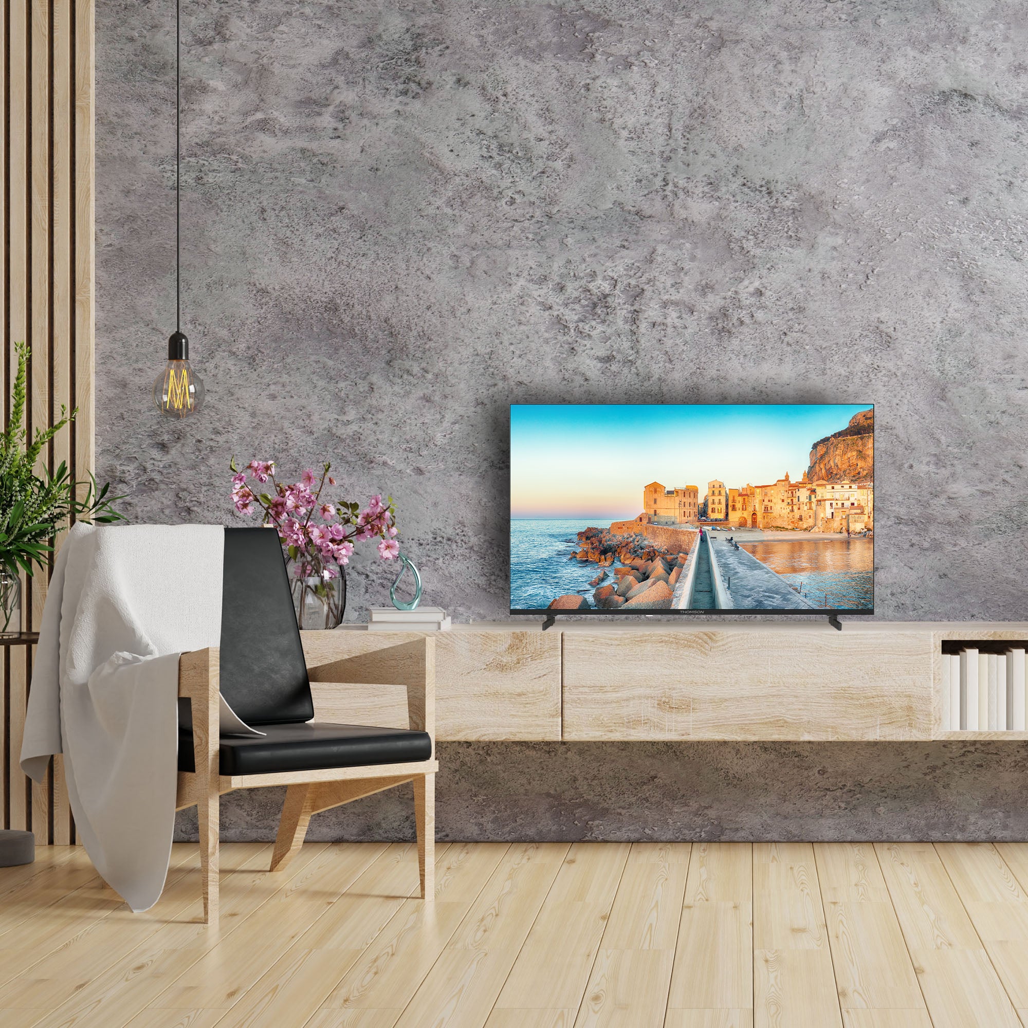 Modern living room with a Thomson TV displaying a scenic image, a chair, and decorative elements.