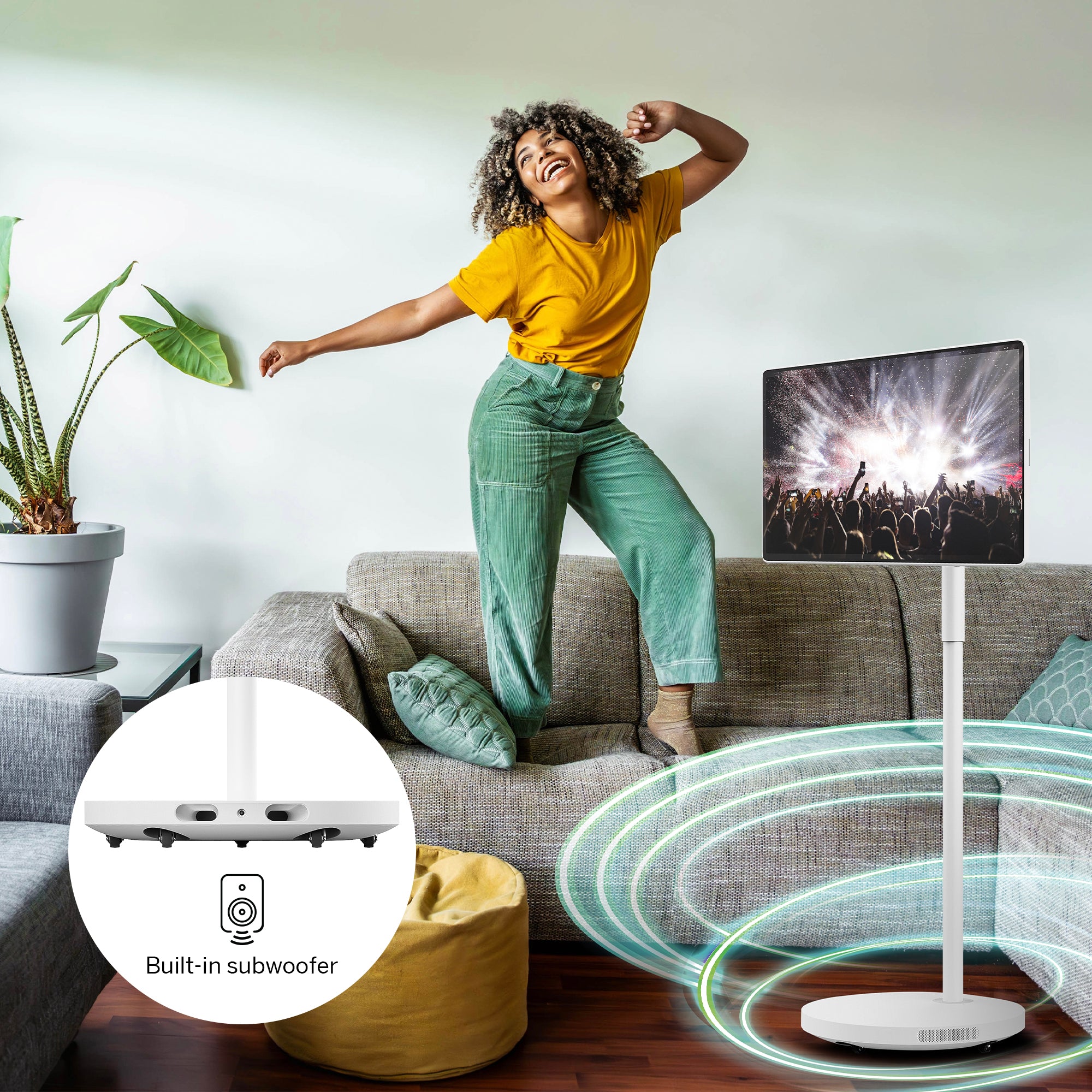 Woman dancing on a couch next to the Thomson Go Plus Pro with subwoofer in a living room.