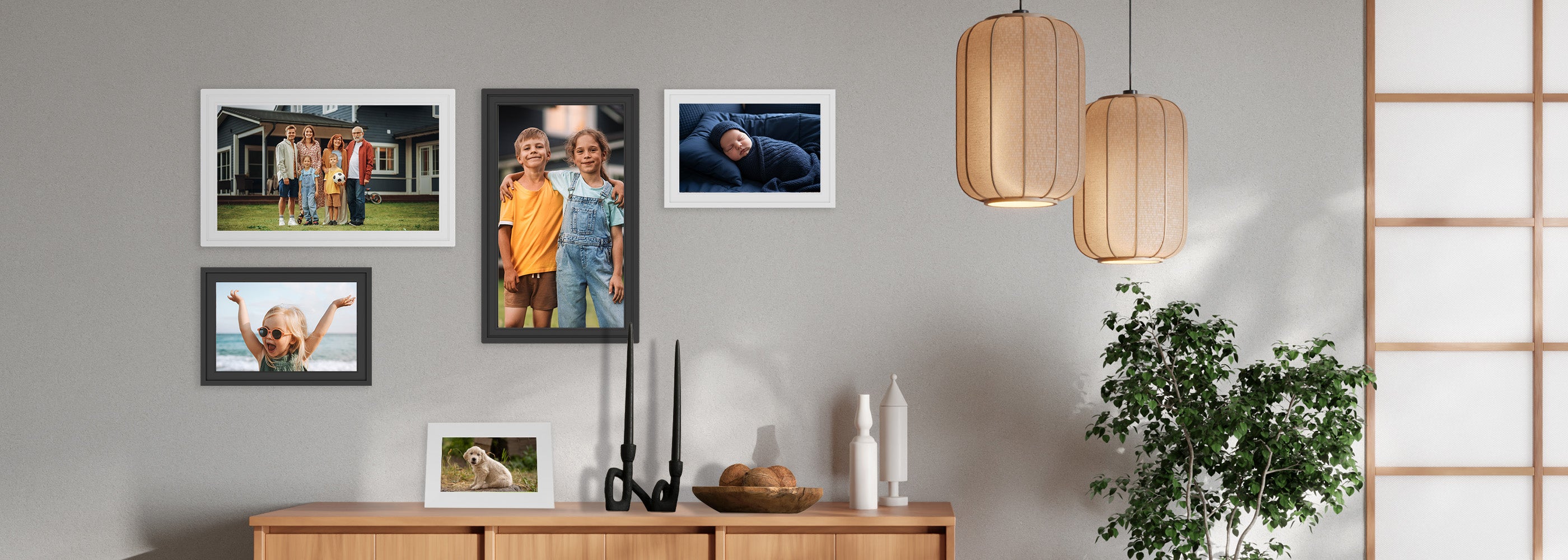 Framed family photos on a wall with a wooden sideboard and decorative items.