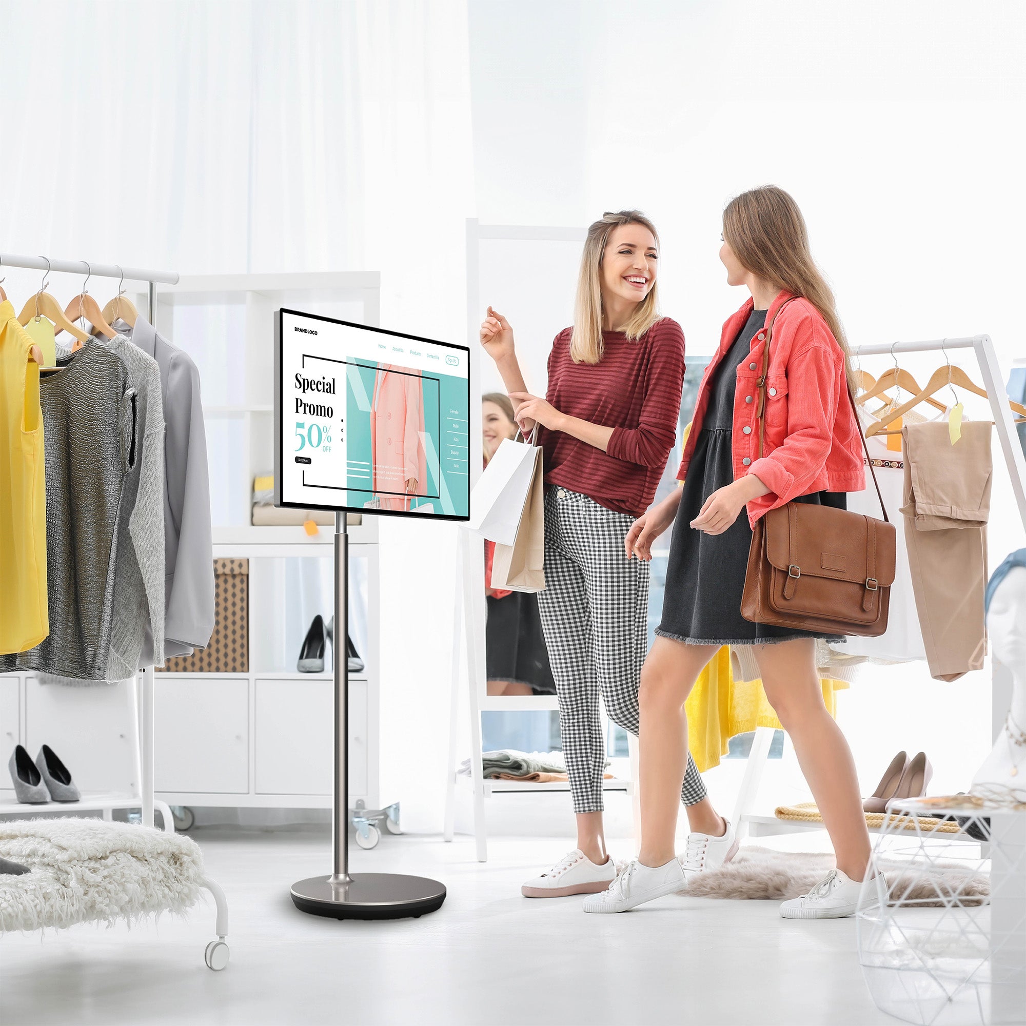 Two women in a clothing store with a digital display showing a special promotion.